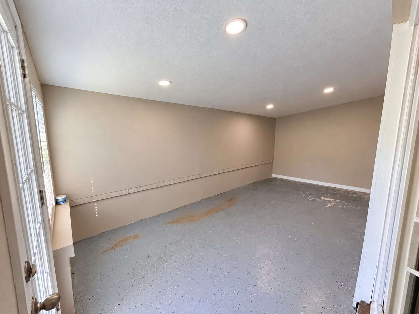 Recessed ceiling lighting, painted walls, and concrete flooring
