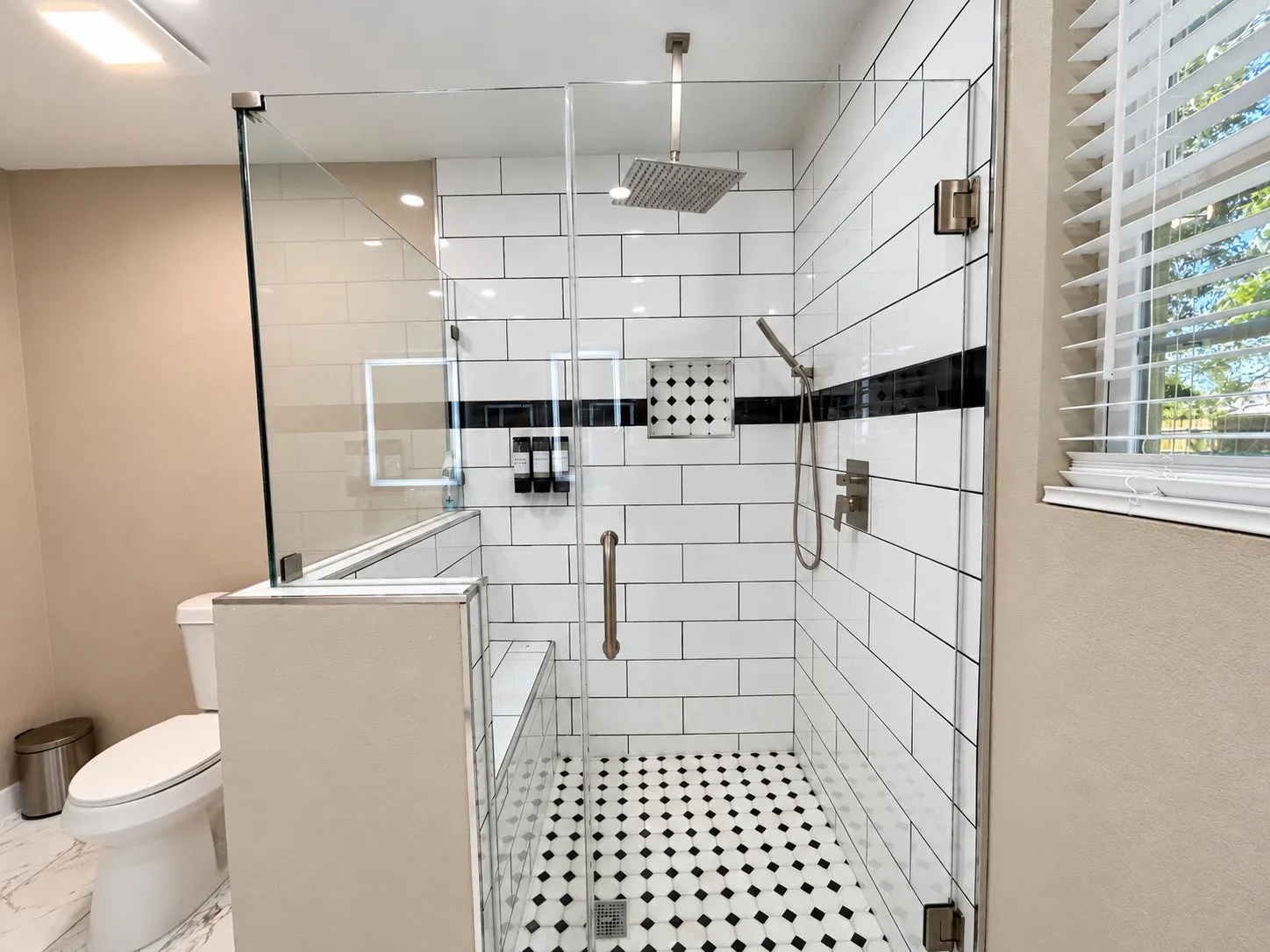 Walk-in shower with clear glass enclosure and black and white tilework