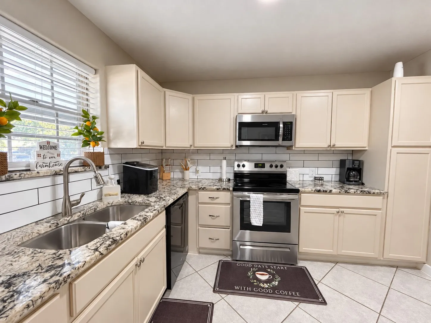 Kitchen featuring light cabinetry, granite-style countertops, white subway tile backsplash, stainless steel appliances, and tile flooring
