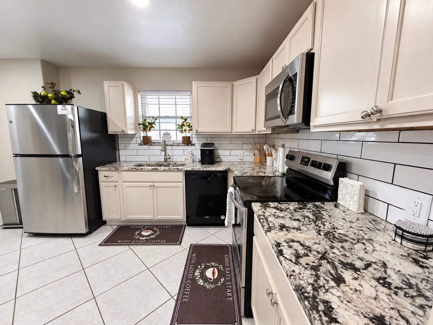 Kitchen featuring white subway tile backsplash, light-toned cabinetry with metal hardware, and granite-style countertops