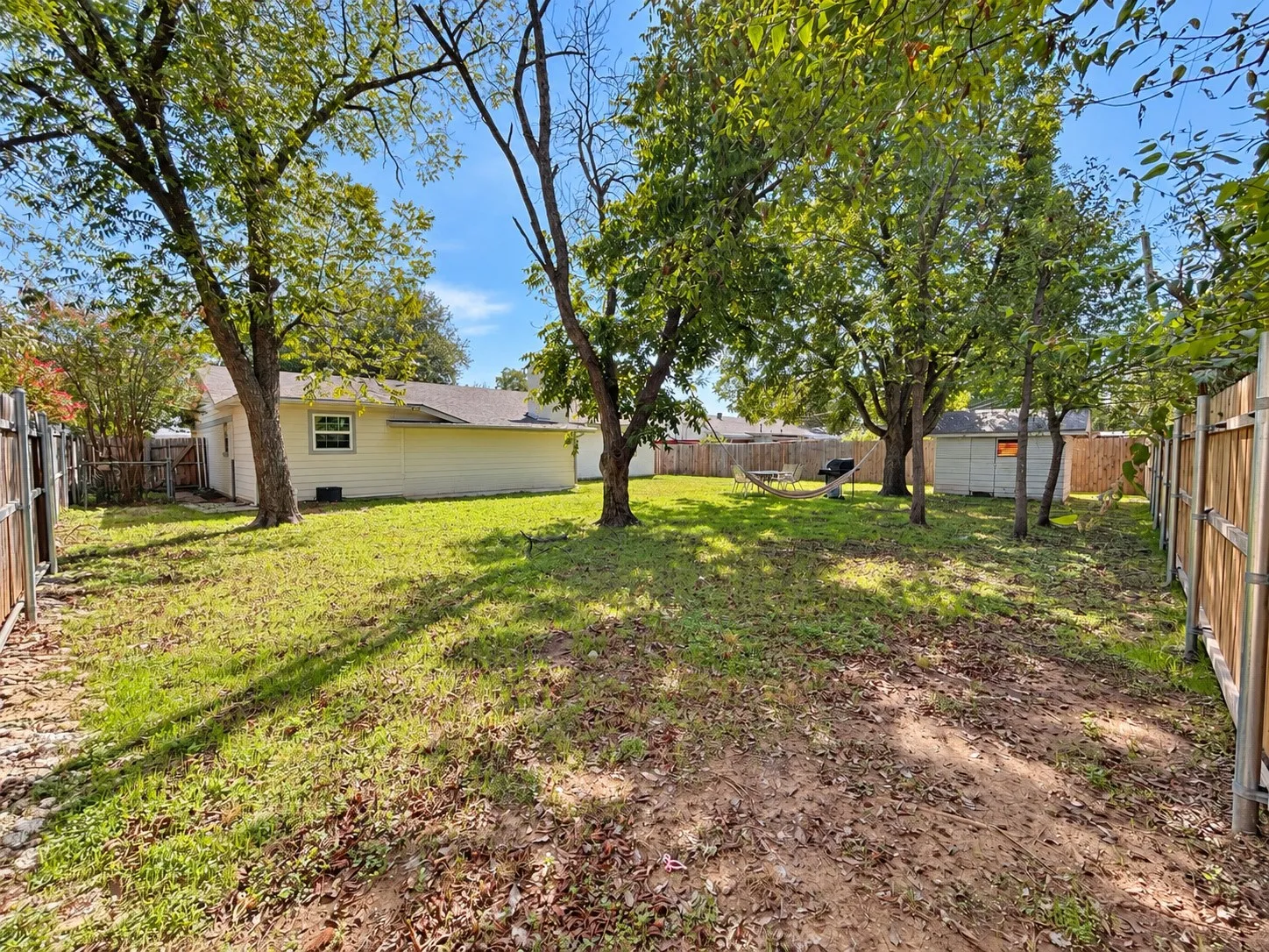 Expansive yard featuring mature trees and a detached shed