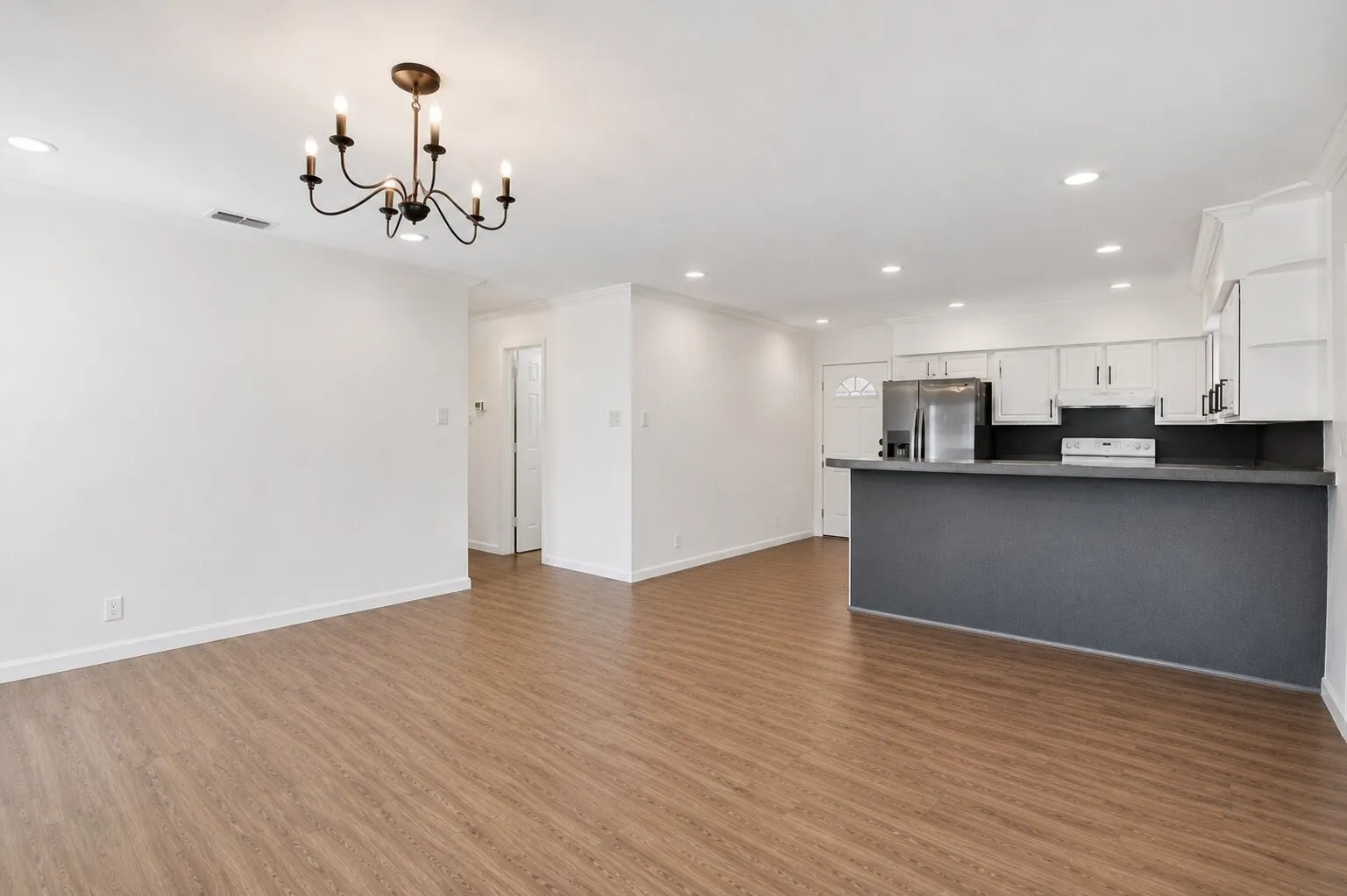 Wood-finish flooring, recessed lighting, and a chandelier in the living area