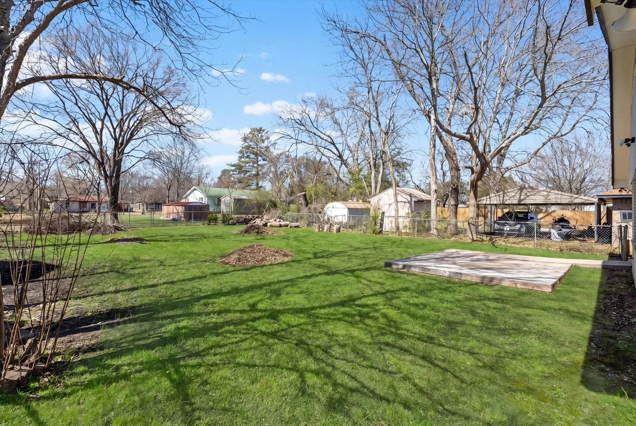 Expansive grassy yard featuring a concrete pad and mature trees