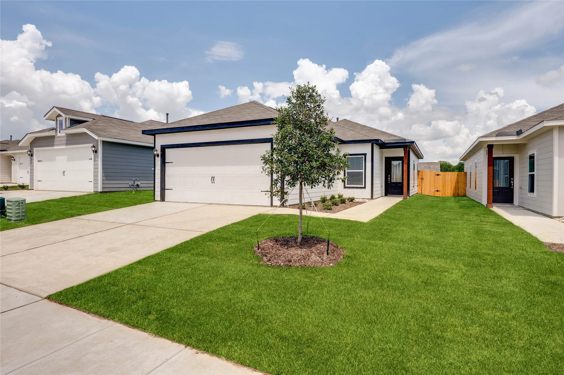 Ranch-style home featuring a garage, driveway, a shingled roof, and a gate