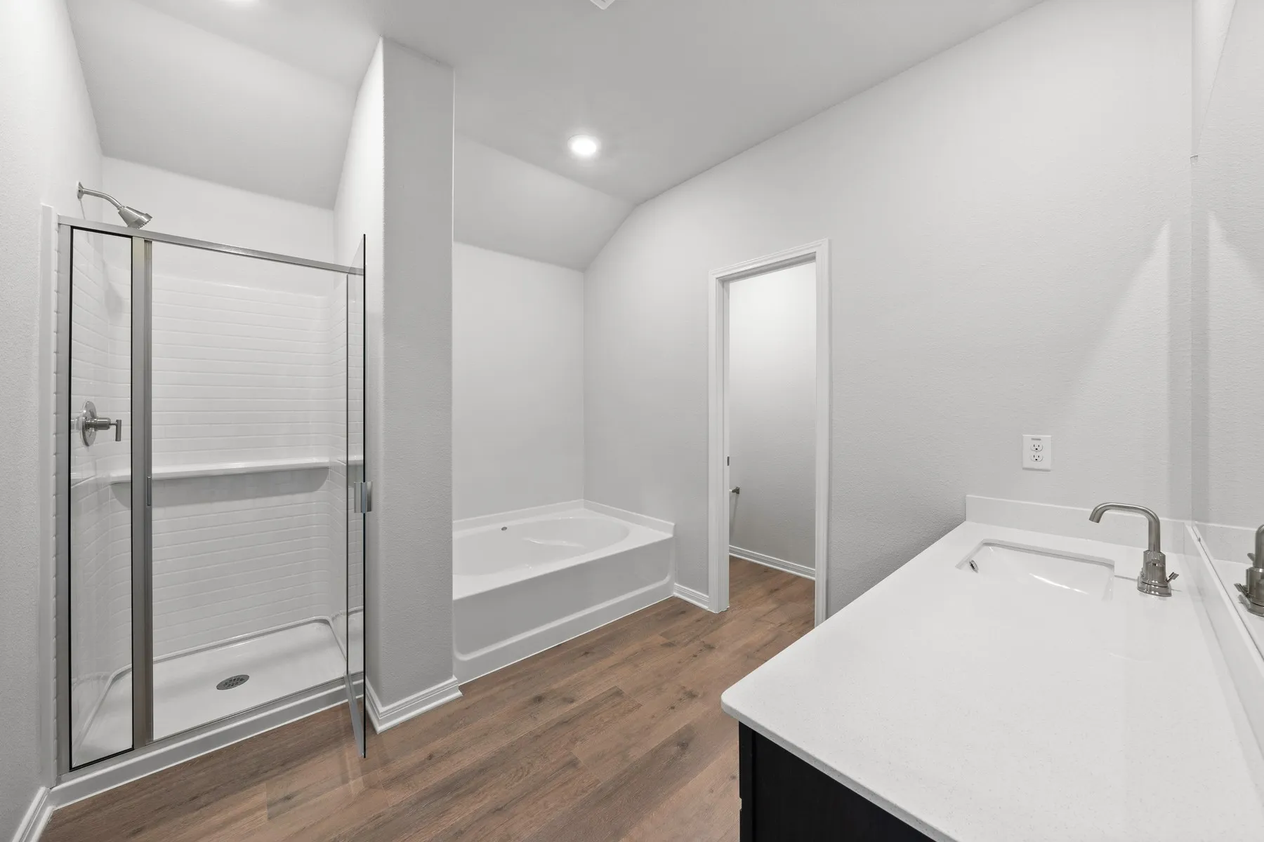 Bathroom with vanity, wood-type flooring, plus walk in shower, and vaulted ceiling