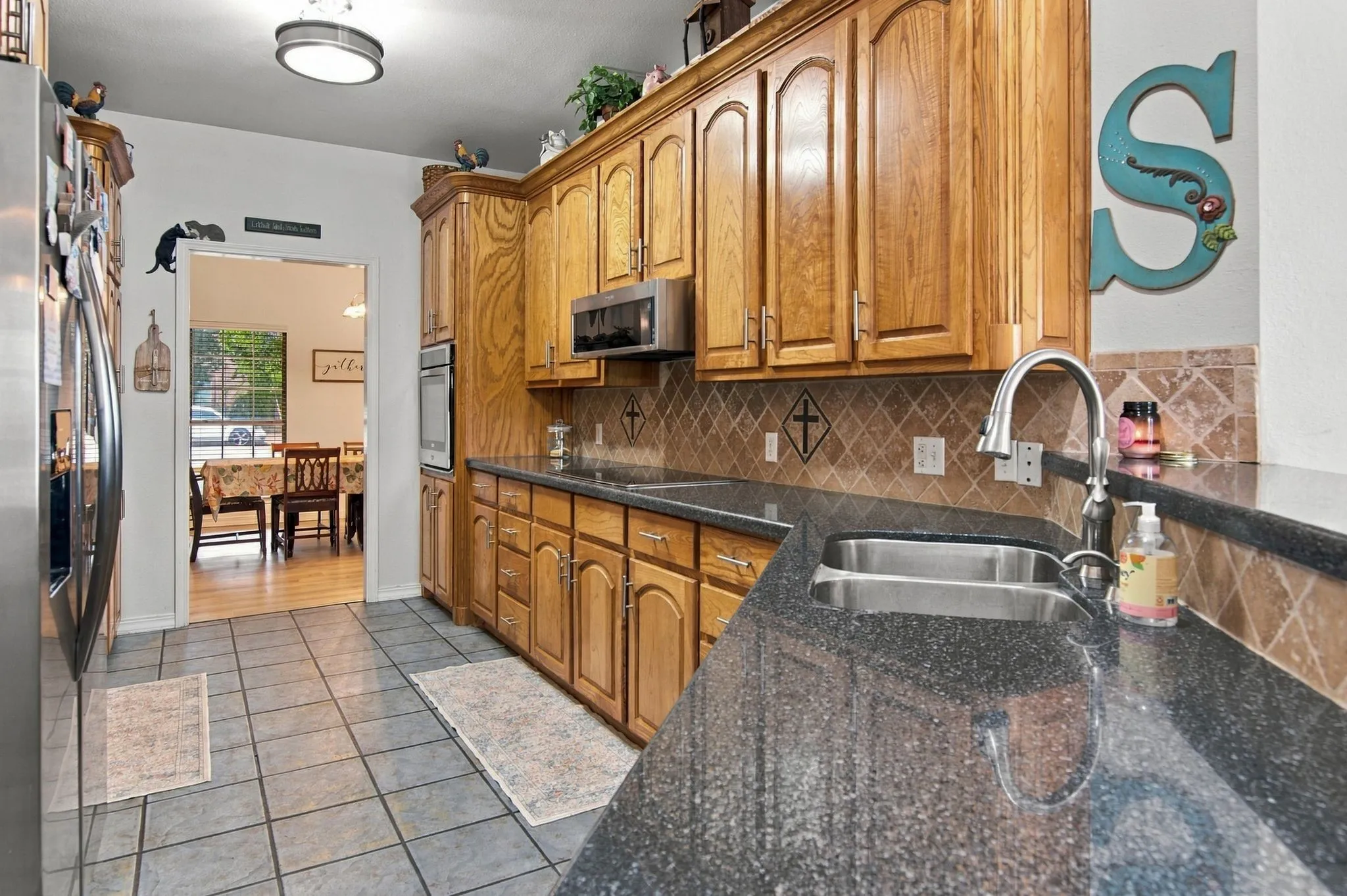 Wood-finish cabinetry paired with dark speckled countertops, stainless steel appliances, and a tiled backsplash