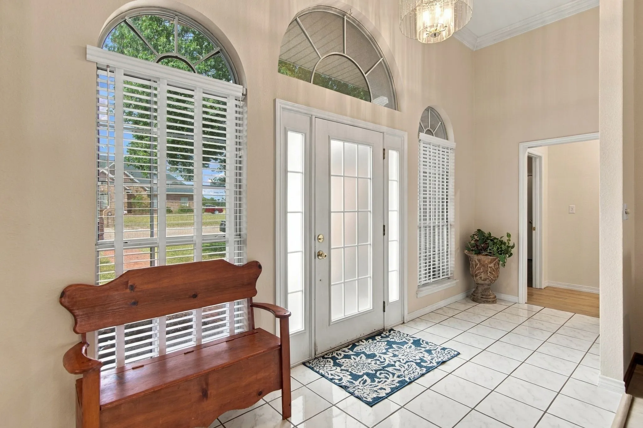 Double-door entry with frosted glass panels, arched transom window, and white tile flooring