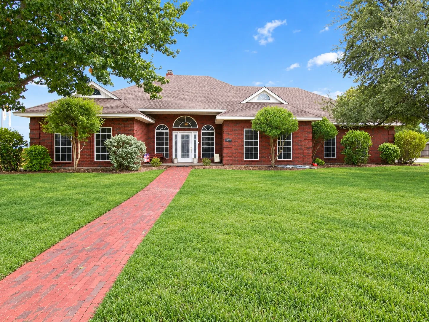 Expansive front lawn with mature trees and a red brick walkway *grass greened