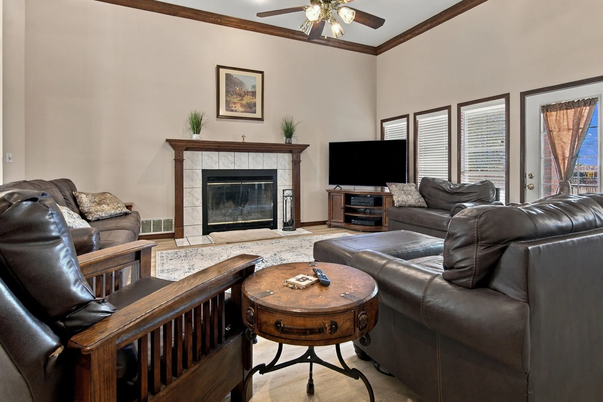 Living area with vaulted ceilings, a fireplace featuring a tile surround and wood mantel, wood-finish flooring, and multiple transom windows