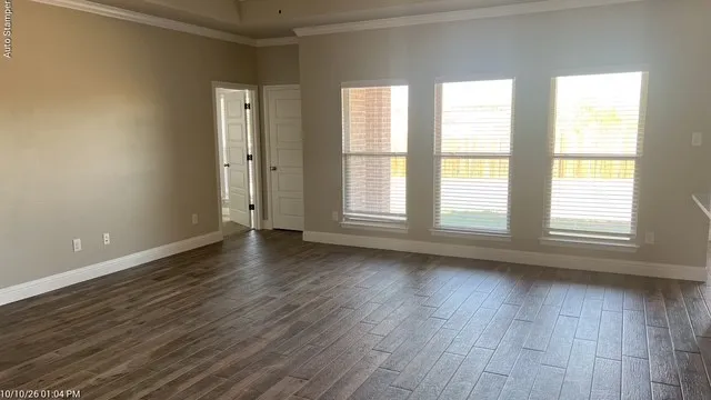 Wood-finish flooring, neutral wall tones, crown molding, and multiple windows with blinds