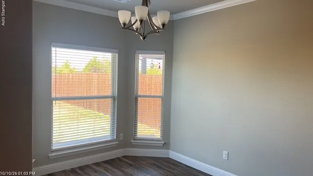Bay window with blinds, wood-finish flooring, contemporary chandelier, crown molding, and neutral wall tones