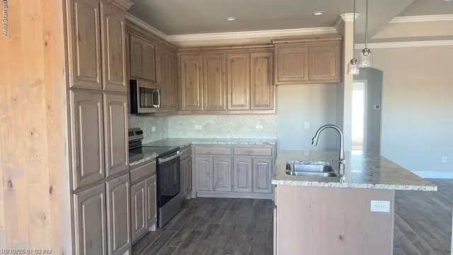 Kitchen featuring wood-finish cabinetry, stainless steel appliances, granite countertops, and a tile backsplash