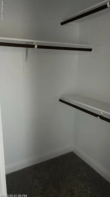 Closet with white walls, built-in shelving, and dark-finish hanging rods