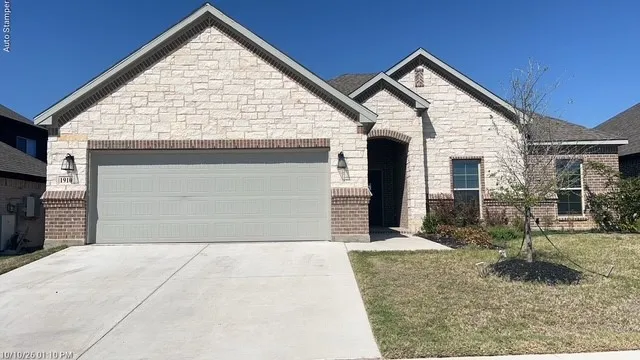 Stone and brick exterior with a two-car garage, arched entry, and gabled roofline
