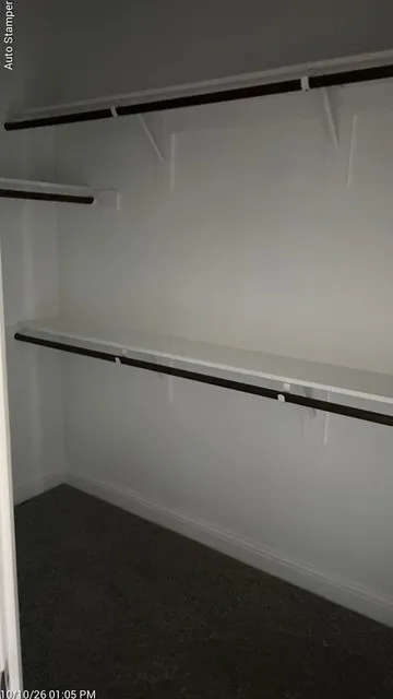 Closet featuring multiple shelving units and hanging rods