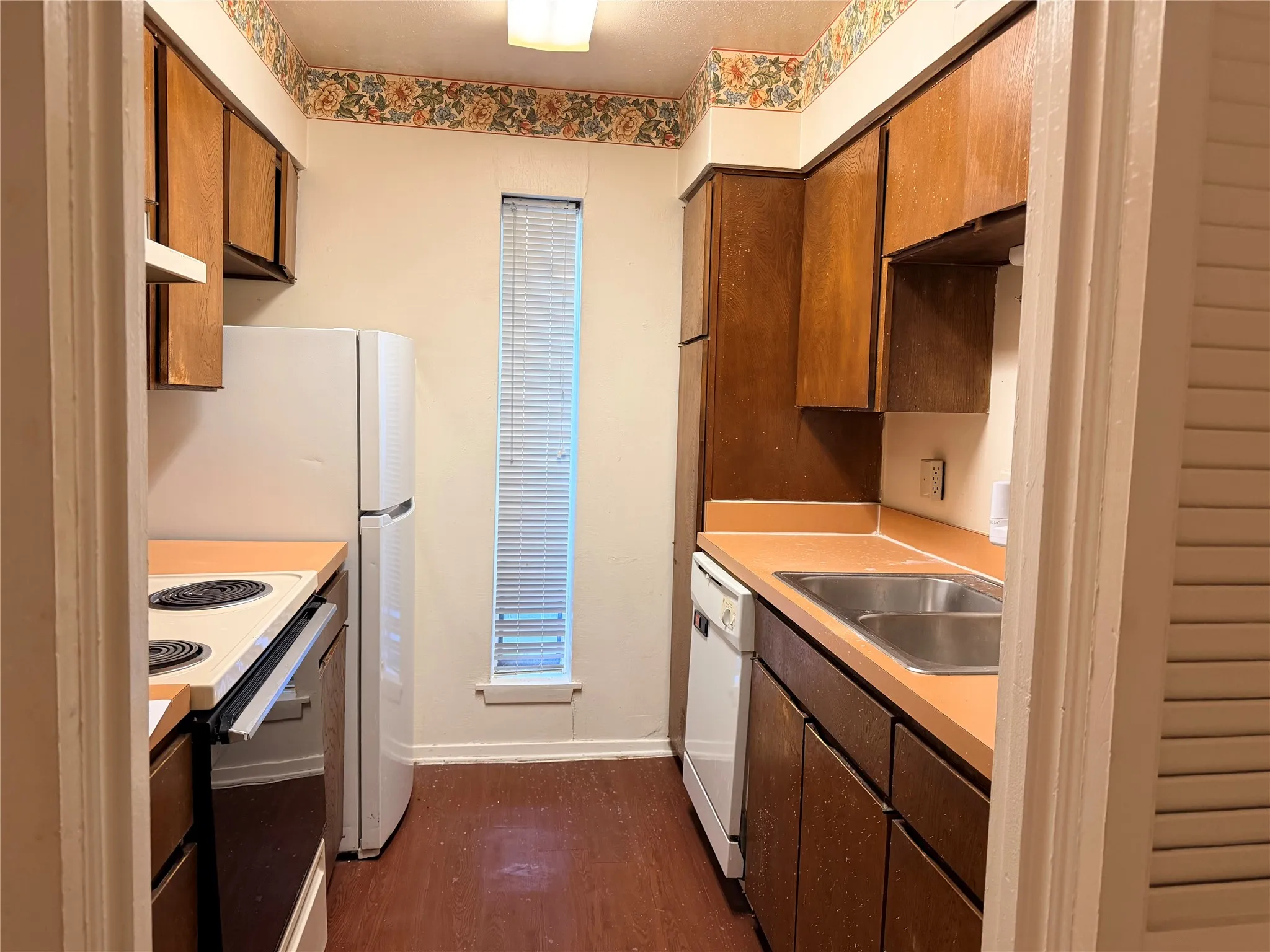 Kitchen featuring wood-finish cabinetry, a double basin stainless steel sink, and a white refrigerator