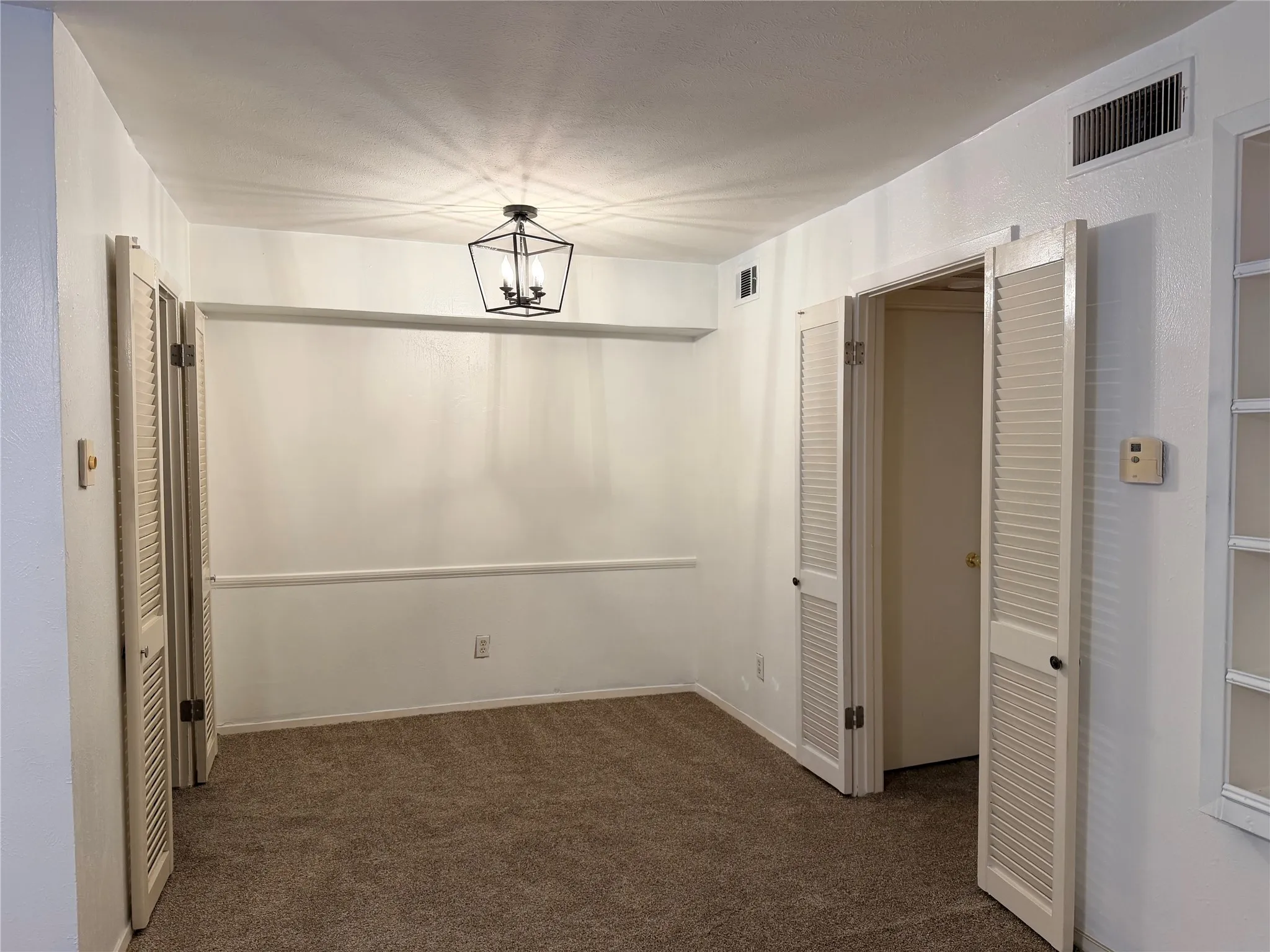 Recessed lighting, ceiling-mounted light fixture, louvered bi-fold doors, white interior paint, and brown carpet flooring
