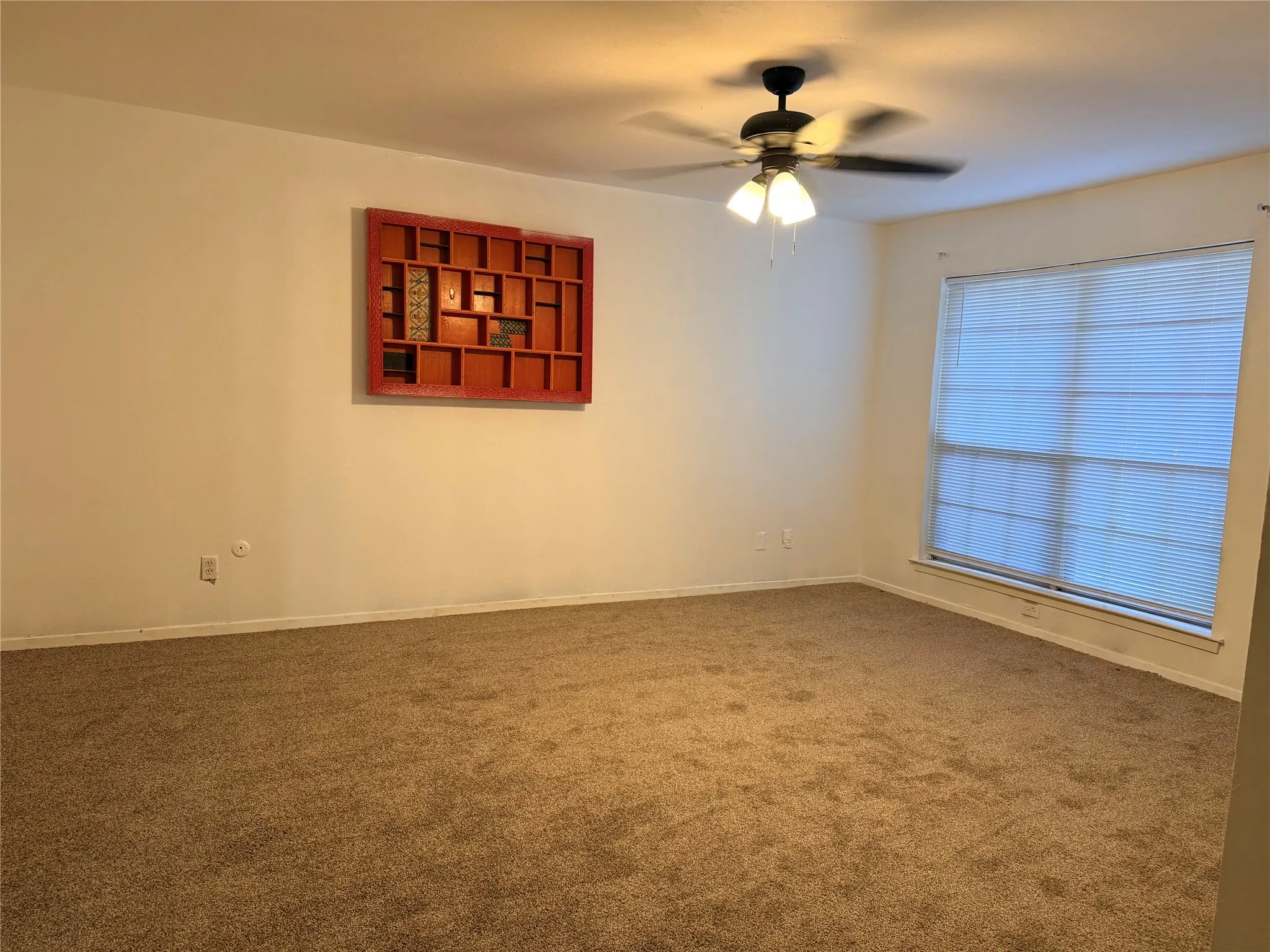 Wall-to-wall carpeting with a ceiling fan light fixture and window with blinds