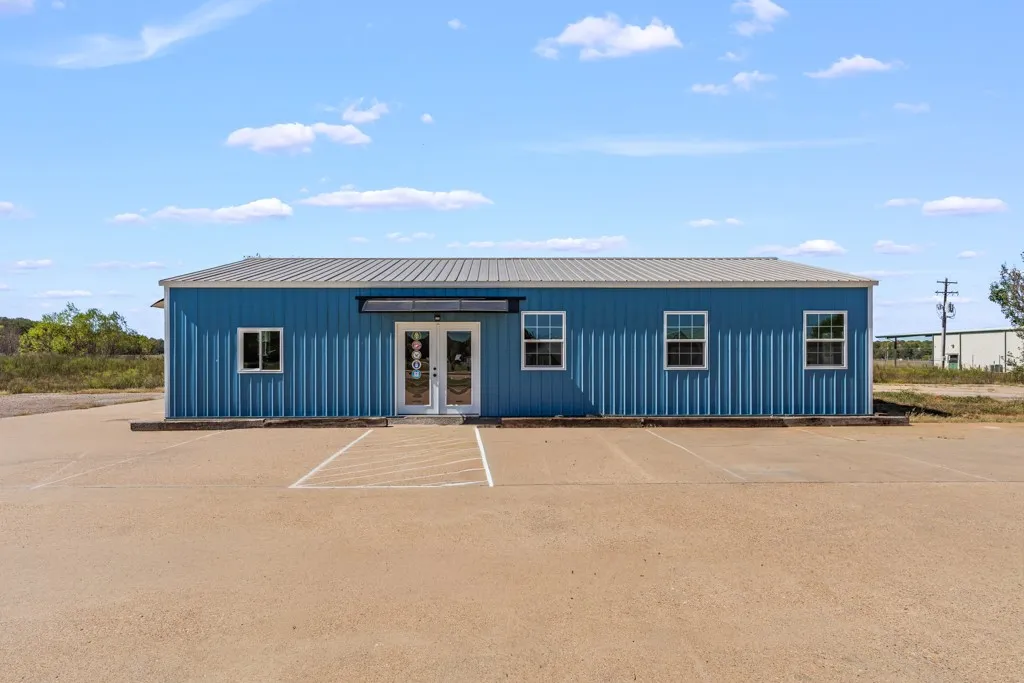 Blue metal siding with a gray metal roof, featuring multiple windows and a double-door entry