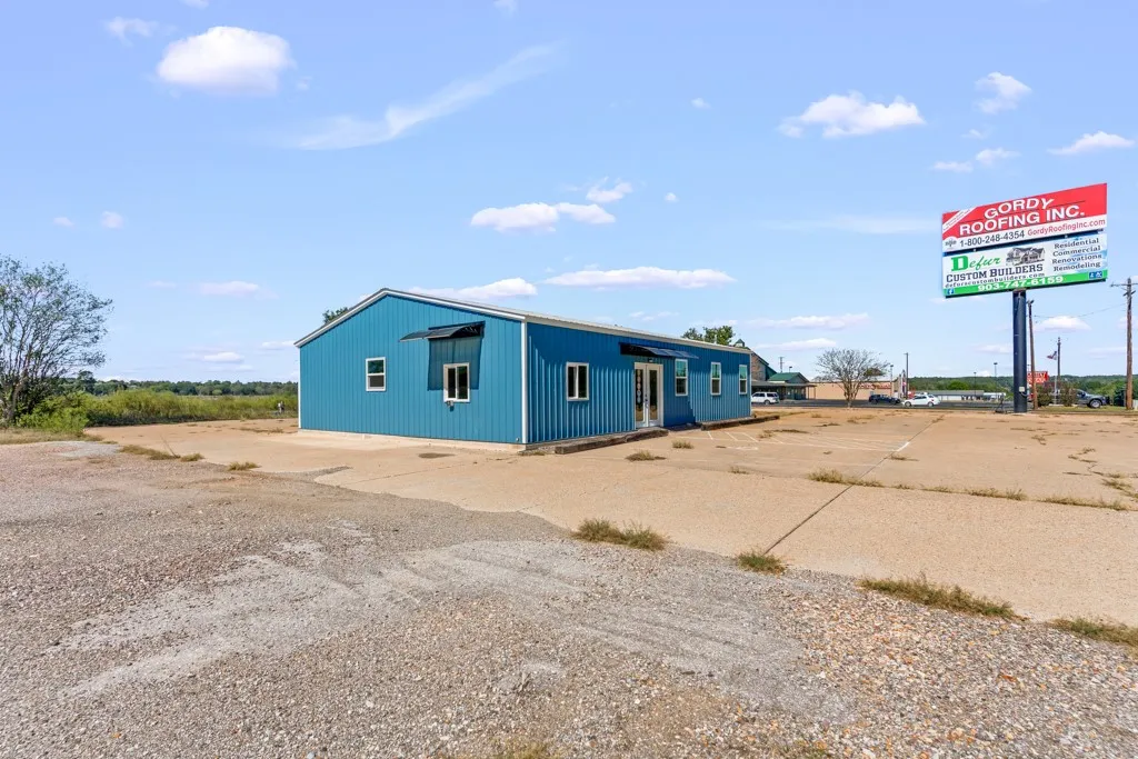 Blue metal-sided commercial building with white trim, multiple windows, and a prominent storefront entrance