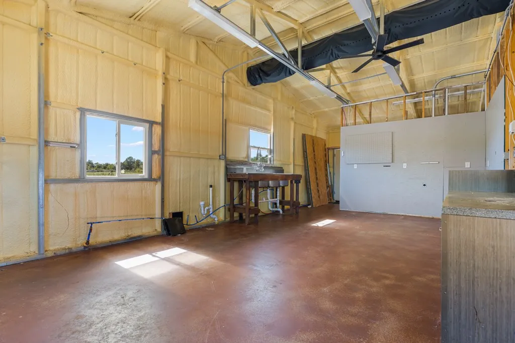 Insulated walls and ceiling with exposed metal framing, concrete flooring, dual-basin sink, and overhead ceiling fan