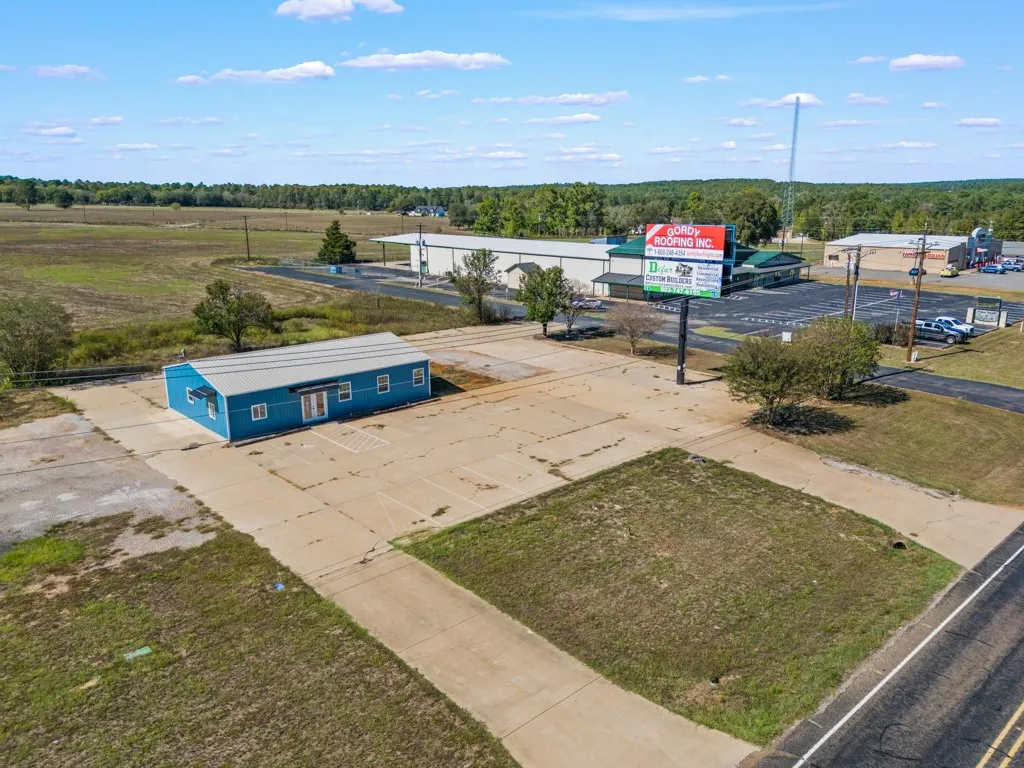 Single-story blue commercial building with a metal roof, multiple windows, and a paved lot