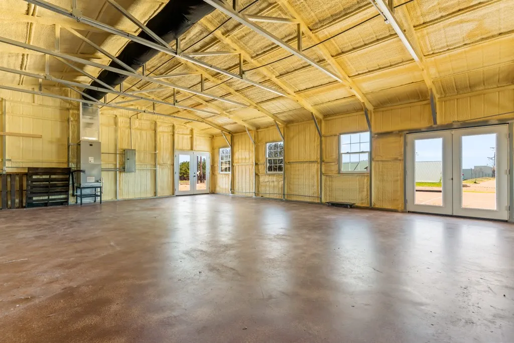 Open-concept structure featuring exposed metal rafters and comprehensive spray foam insulation