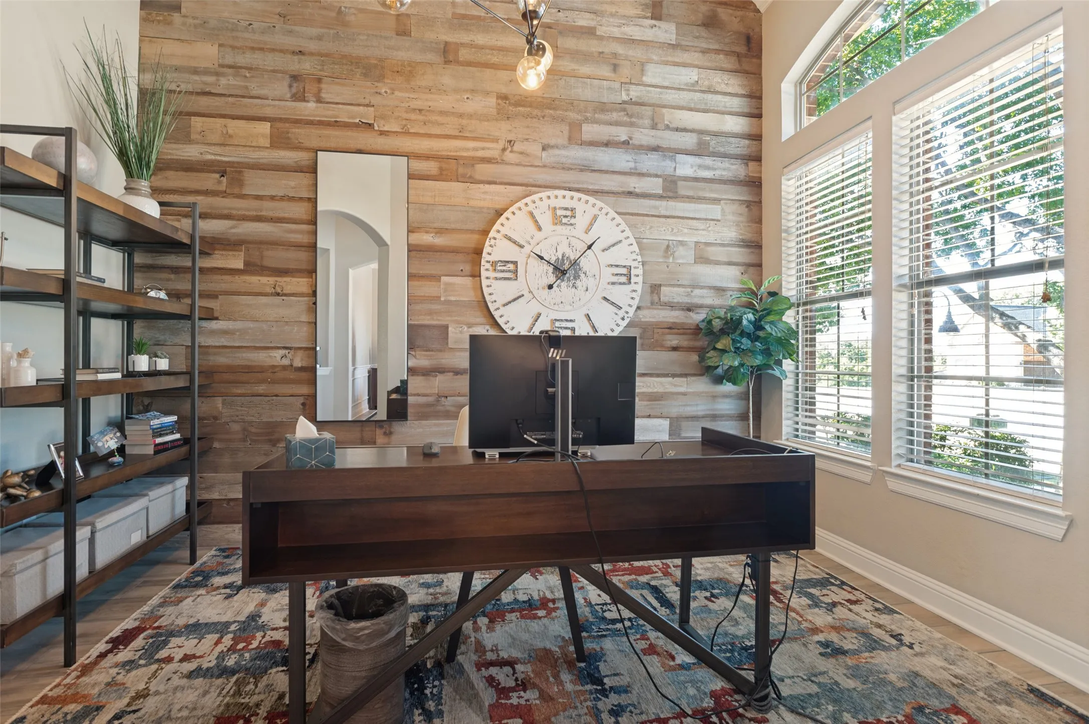 Wood-panel accent wall, vaulted ceiling, and multiple large windows with blinds