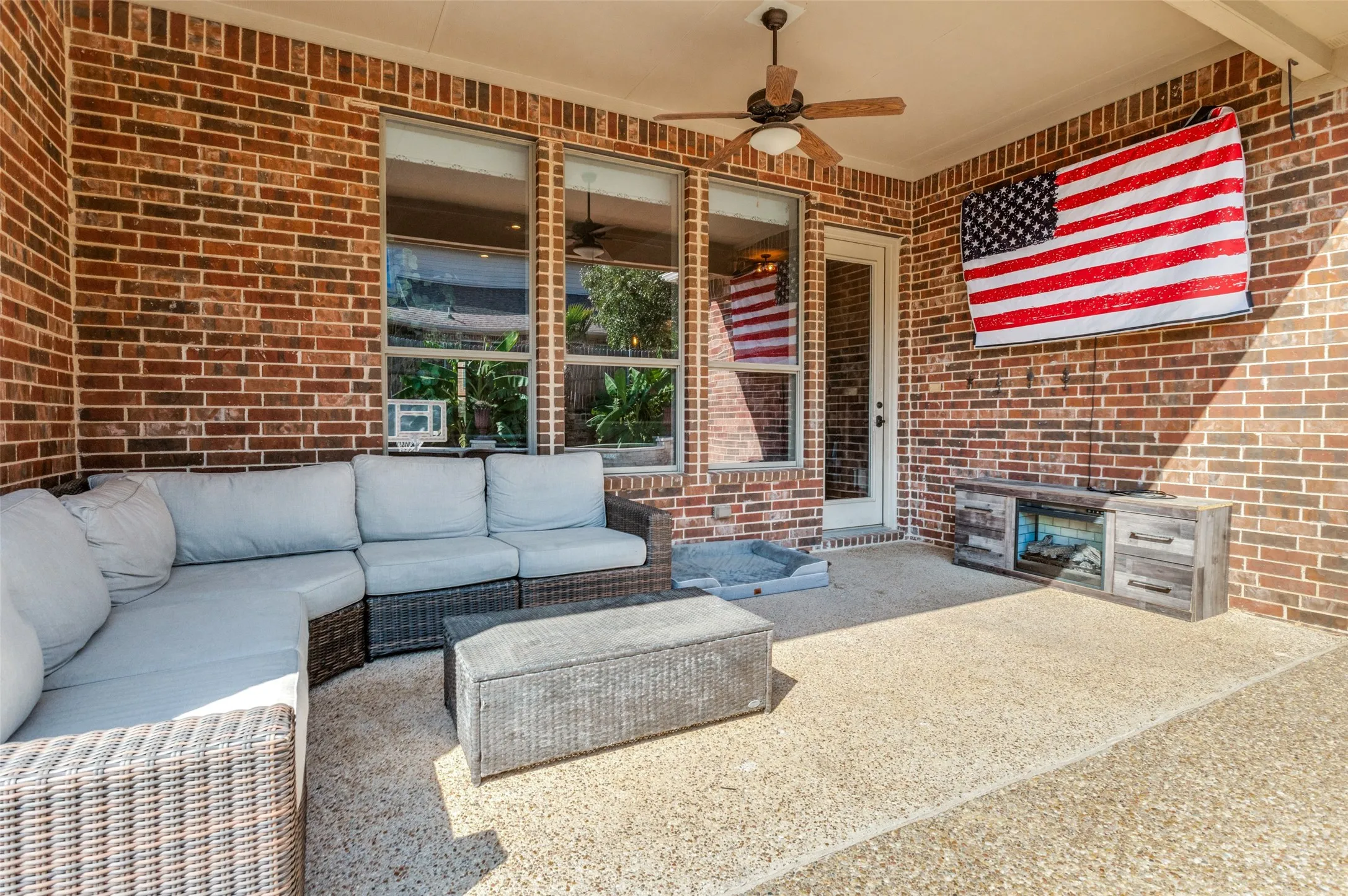 Covered patio featuring a brick exterior wall, a ceiling fan, and multiple windows