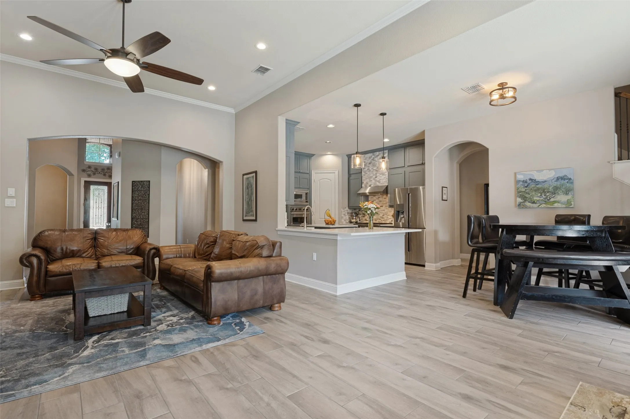 Wood-finish flooring throughout, recessed ceiling lighting, vaulted ceiling, arched doorways, and a kitchen island with pendant lighting