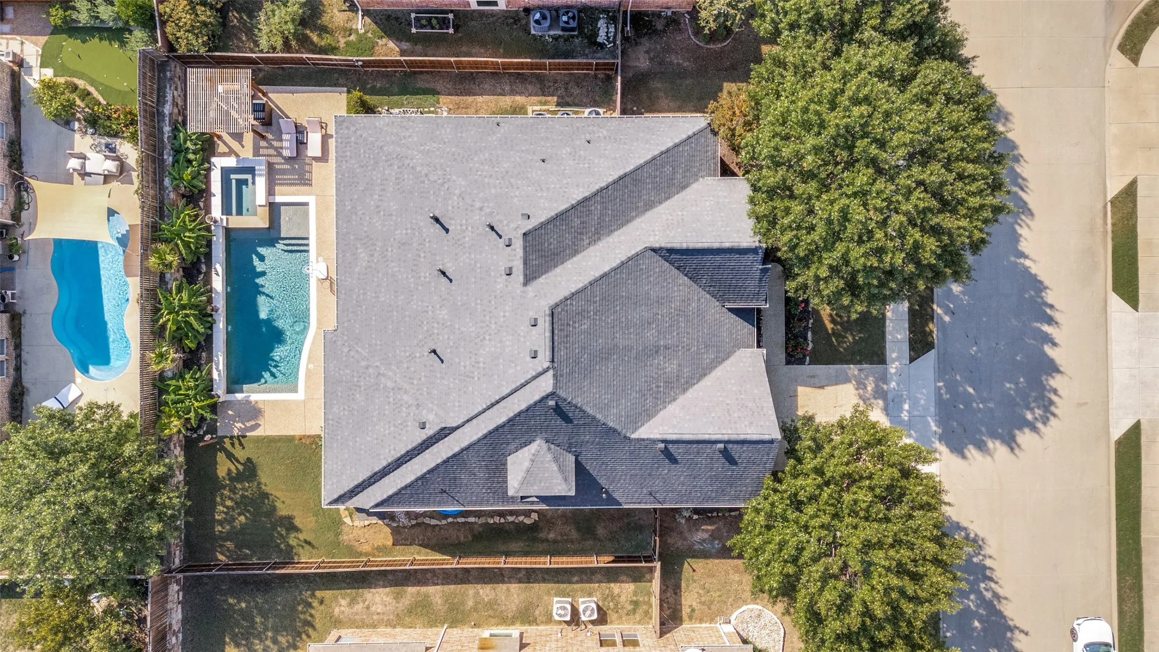 Roof with multiple gables, outdoor pool, spa, and a paved patio area