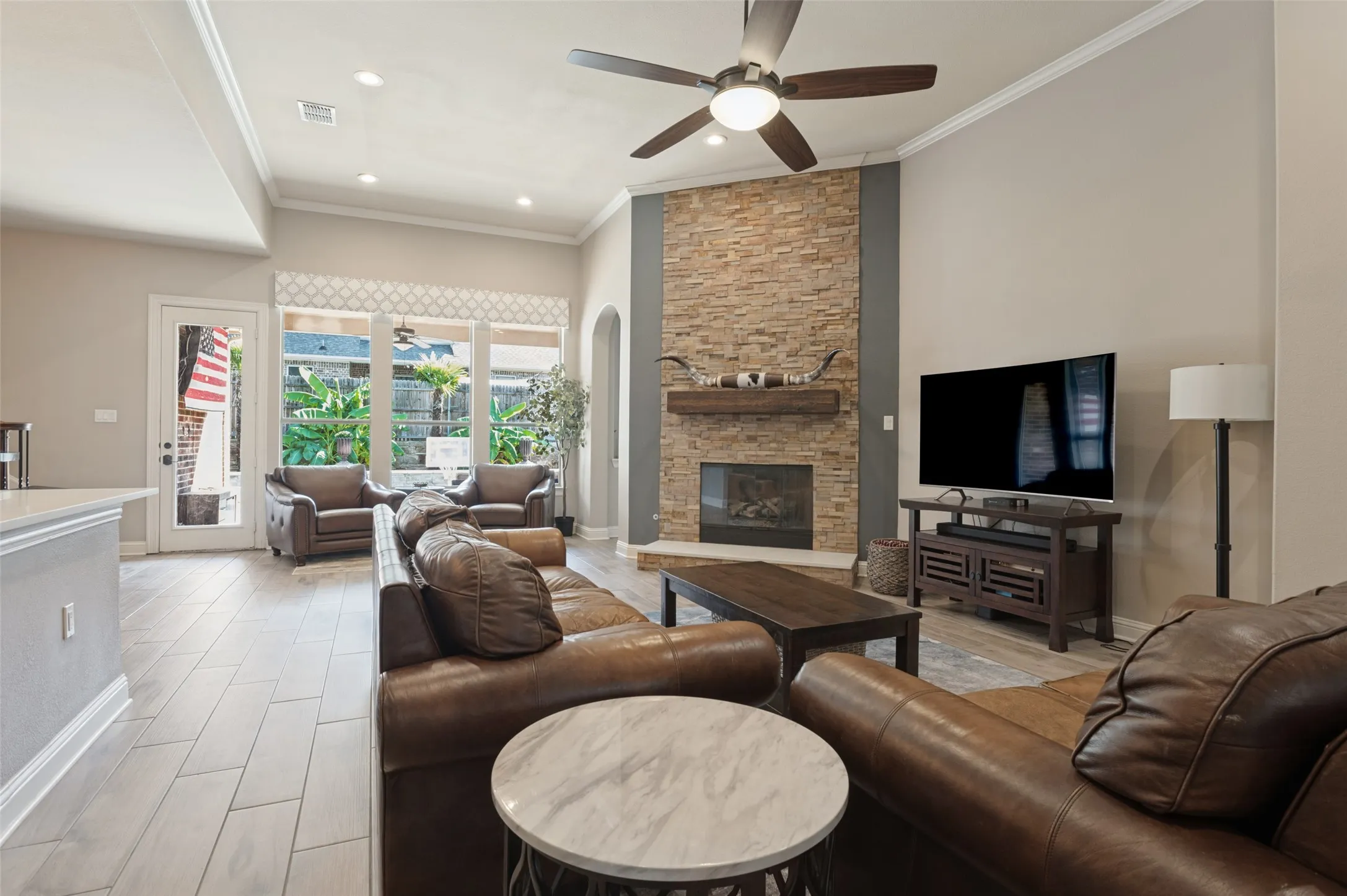 Living area featuring vaulted ceilings, a stone-clad fireplace with wood mantel, wood-finish flooring, and recessed lighting