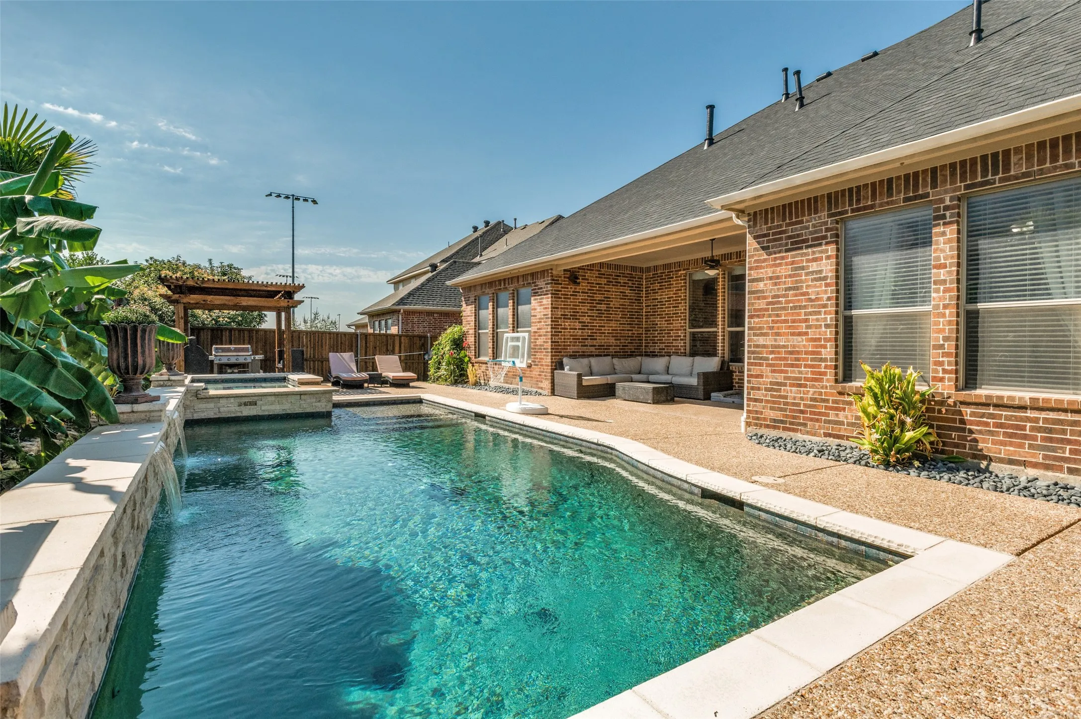 In-ground swimming pool with integrated spa and waterfall feature