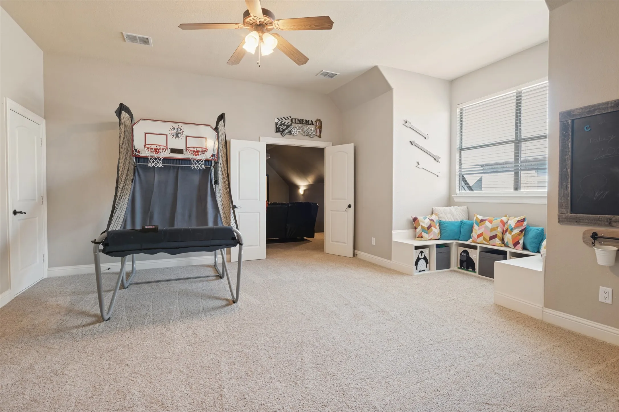 Carpeted room featuring a ceiling fan, built-in window seating with cubby storage, and a single window with blinds