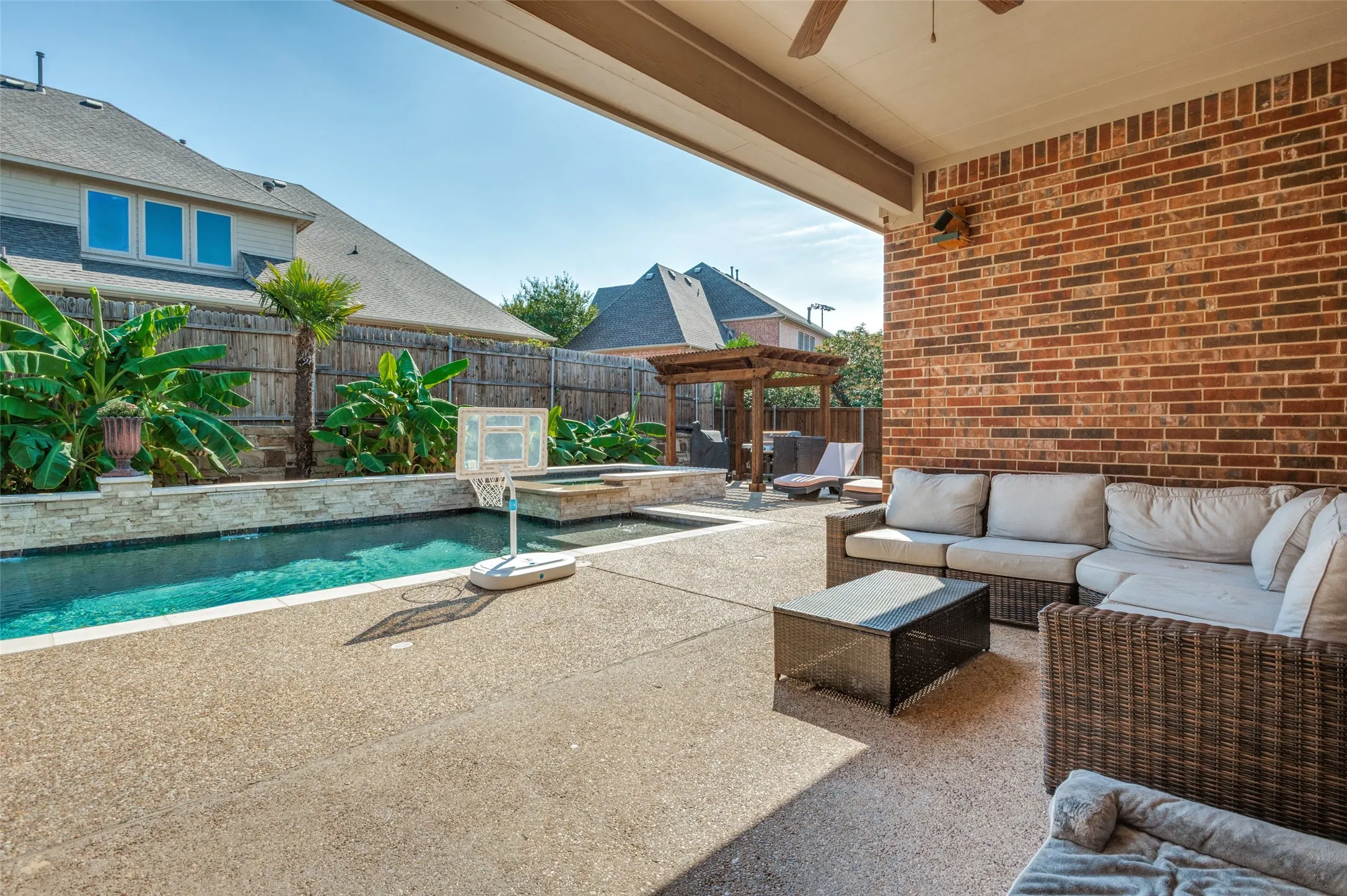 Expansive covered patio with brick exterior, ceiling fan, and concrete-finish flooring