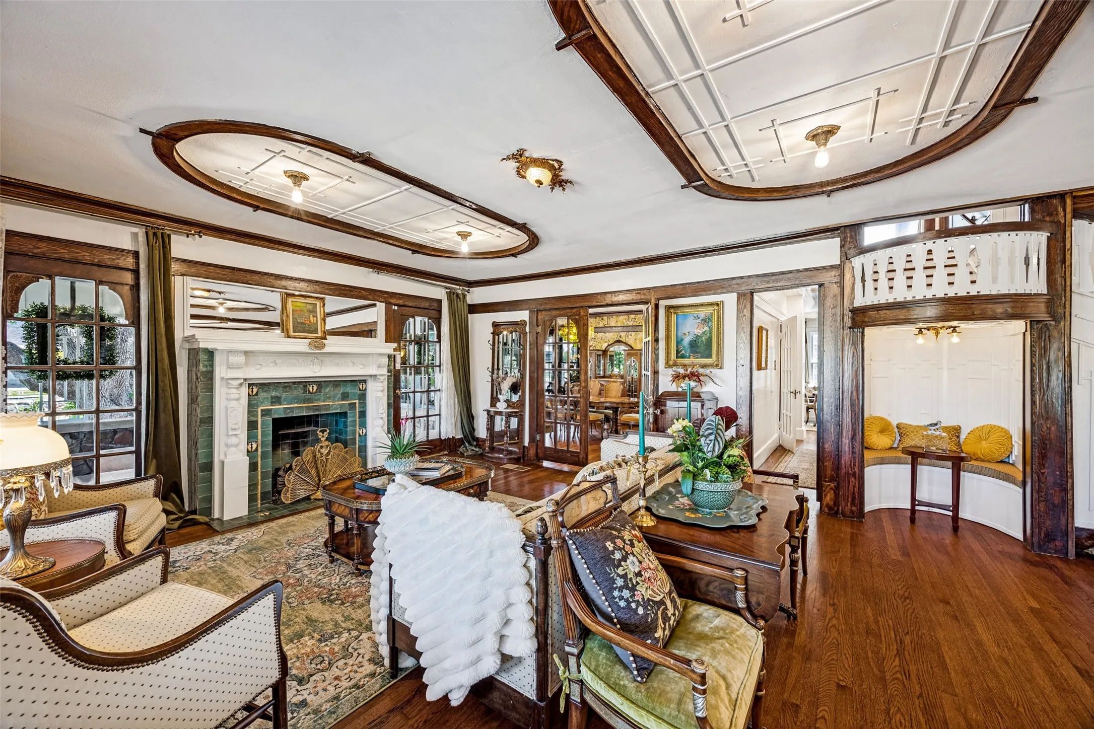 Hardwood flooring, decorative ceiling details, built-in fireplace with a tile surround, and an integrated window seat