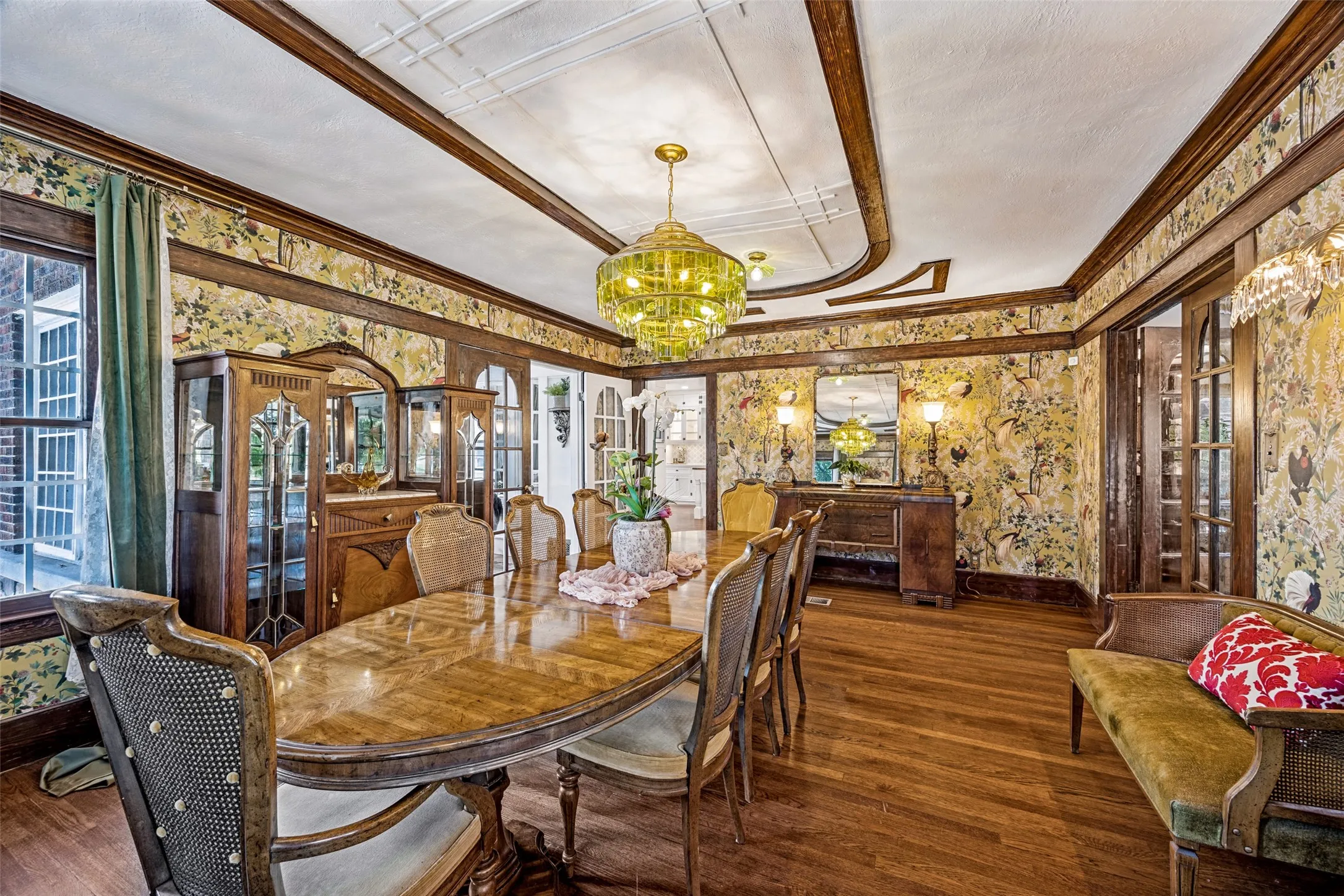 Hardwood flooring, decorative ceiling trim, ornate chandelier, patterned wall coverings, and built-in wood cabinetry