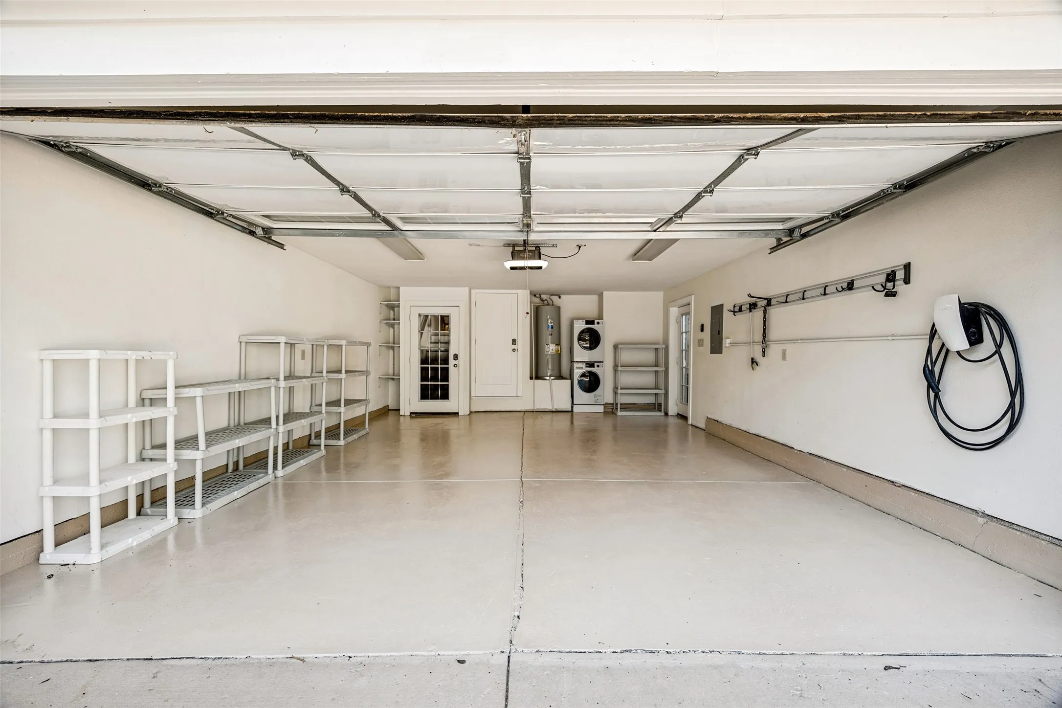 Garage featuring an epoxy floor, built-in shelving, laundry appliances, a water heater, and an EV charging station