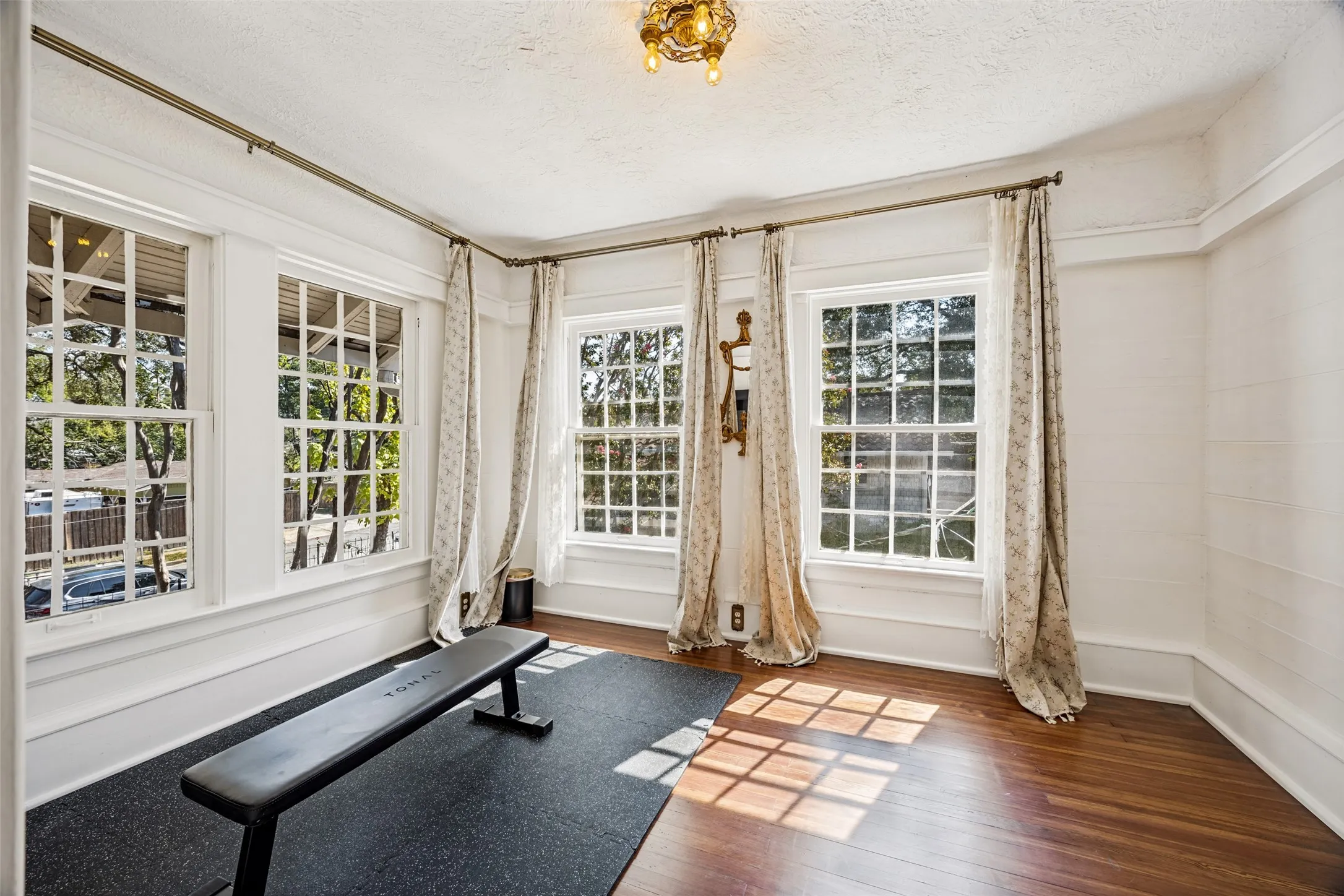 Wood-finish flooring with a multi-pane window configuration and decorative overhead lighting