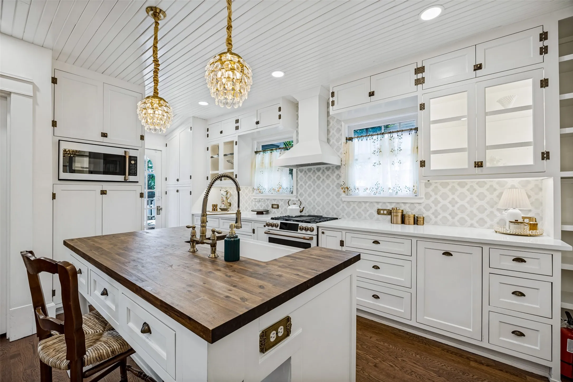 White cabinetry with glass-front accents, dark wood-finish flooring, a kitchen island featuring a wood-finish countertop, and a white farmhouse sink