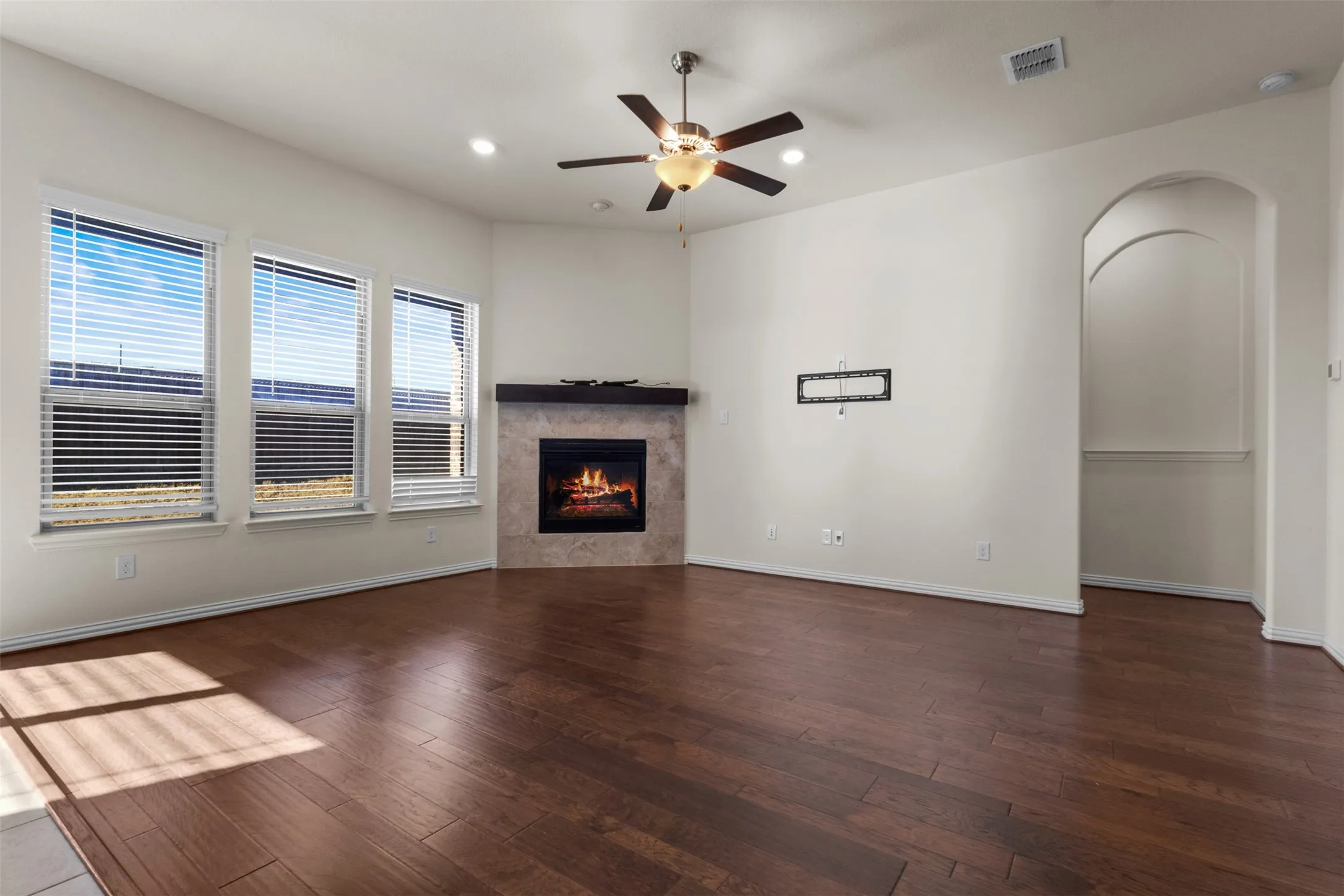 Wood-finish flooring throughout, featuring a corner fireplace with a tiled surround and dark wood mantel