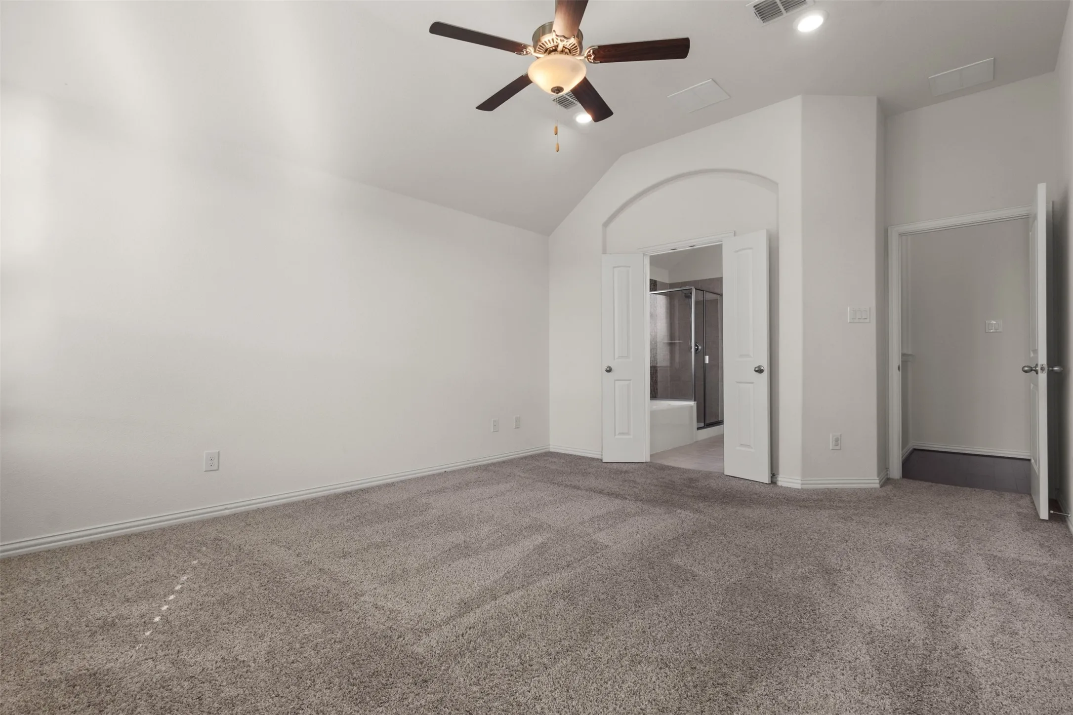 Carpeted flooring, vaulted ceiling, ceiling fan with integrated lighting, recessed lighting, and an arched entryway