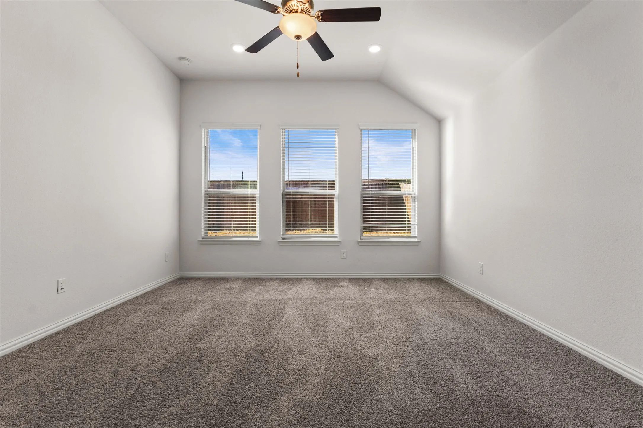 High vaulted ceiling with a ceiling fan, three windows with blinds, recessed lighting, and carpet flooring