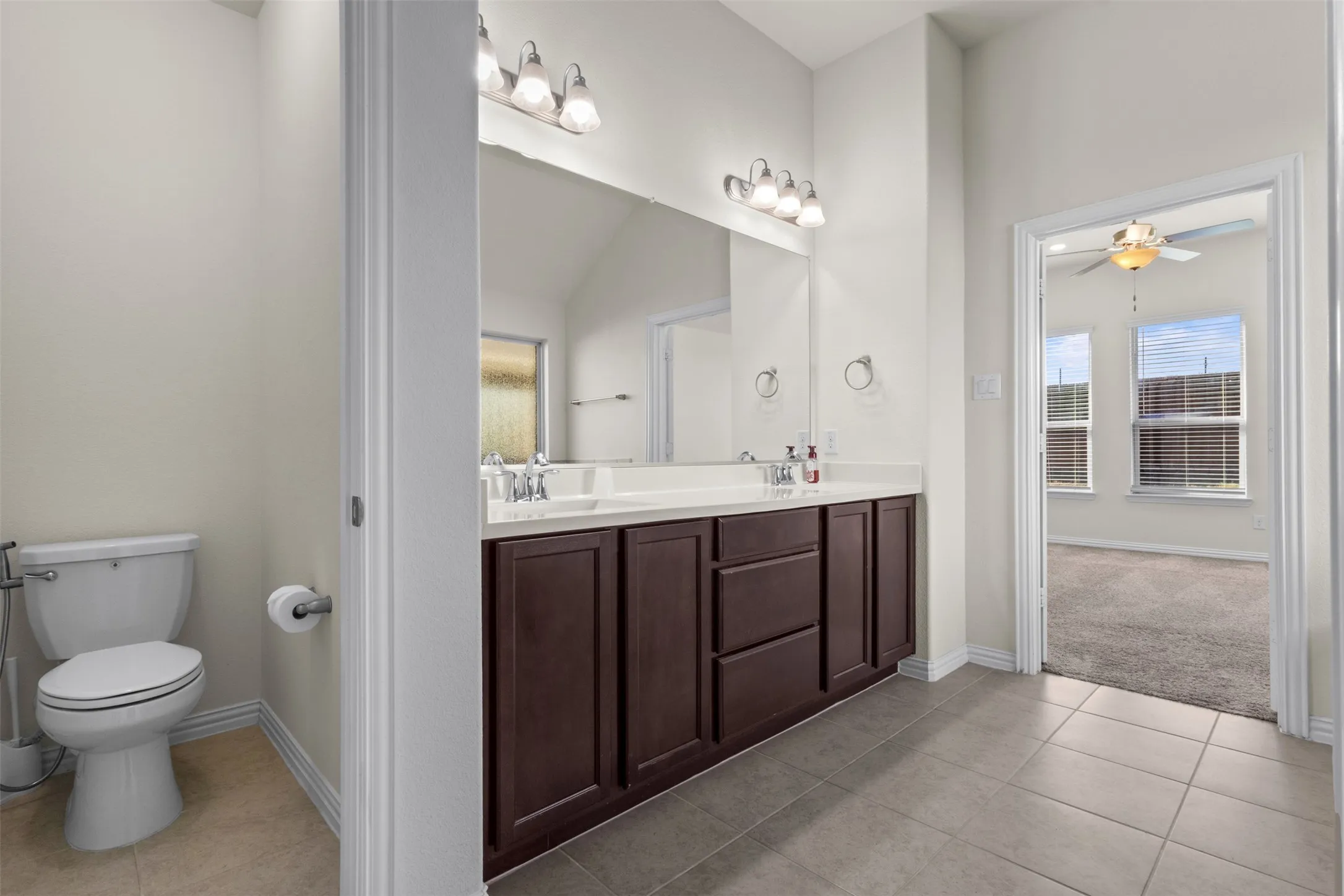 Dual vanity with white countertop, chrome fixtures, and dark wood-finish cabinetry