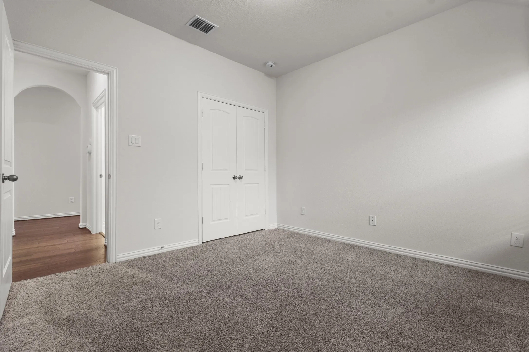 Plush carpet flooring, white painted walls, and a double-door closet