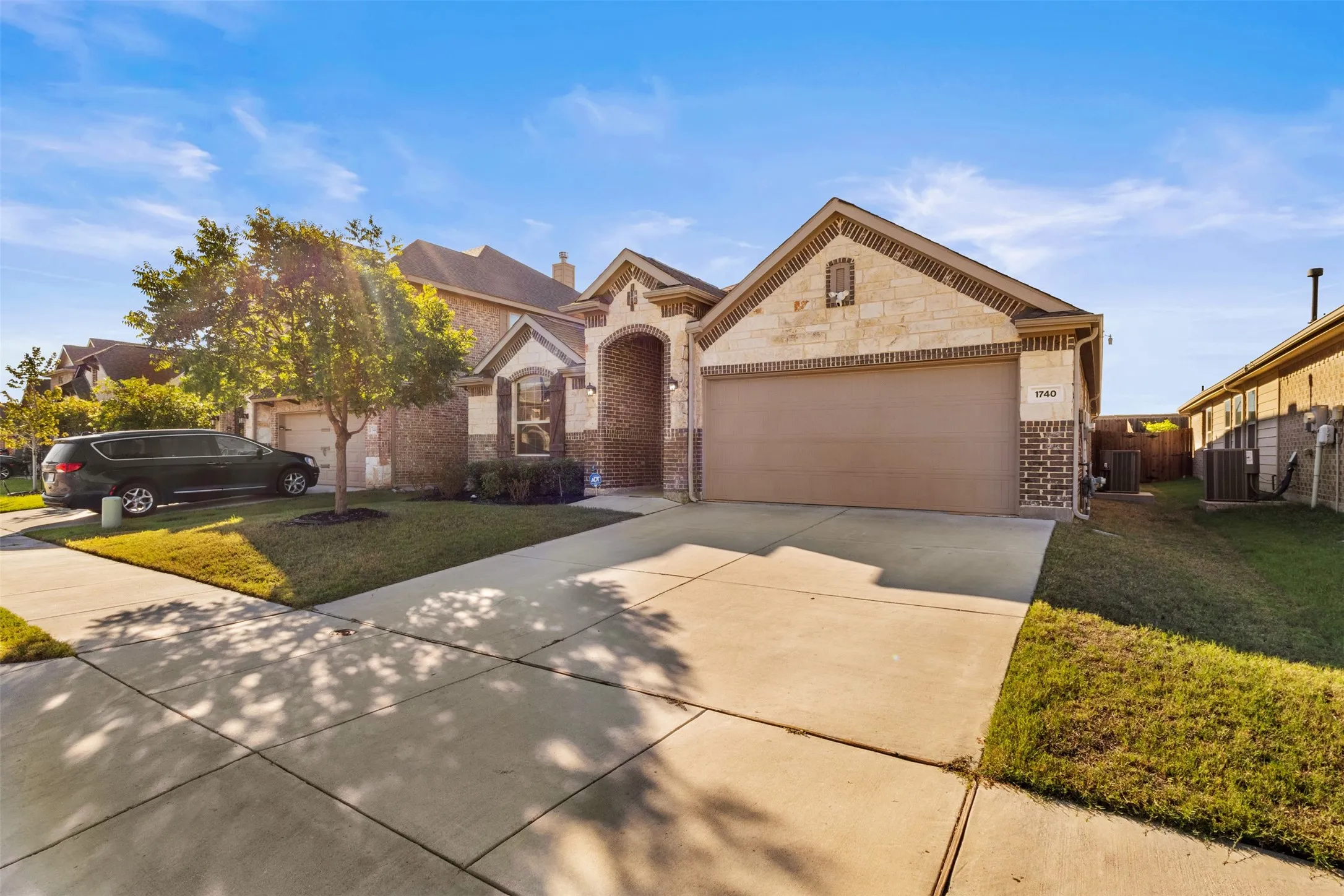 Brick and stone exterior with an arched entry, a two-car garage, and a concrete driveway