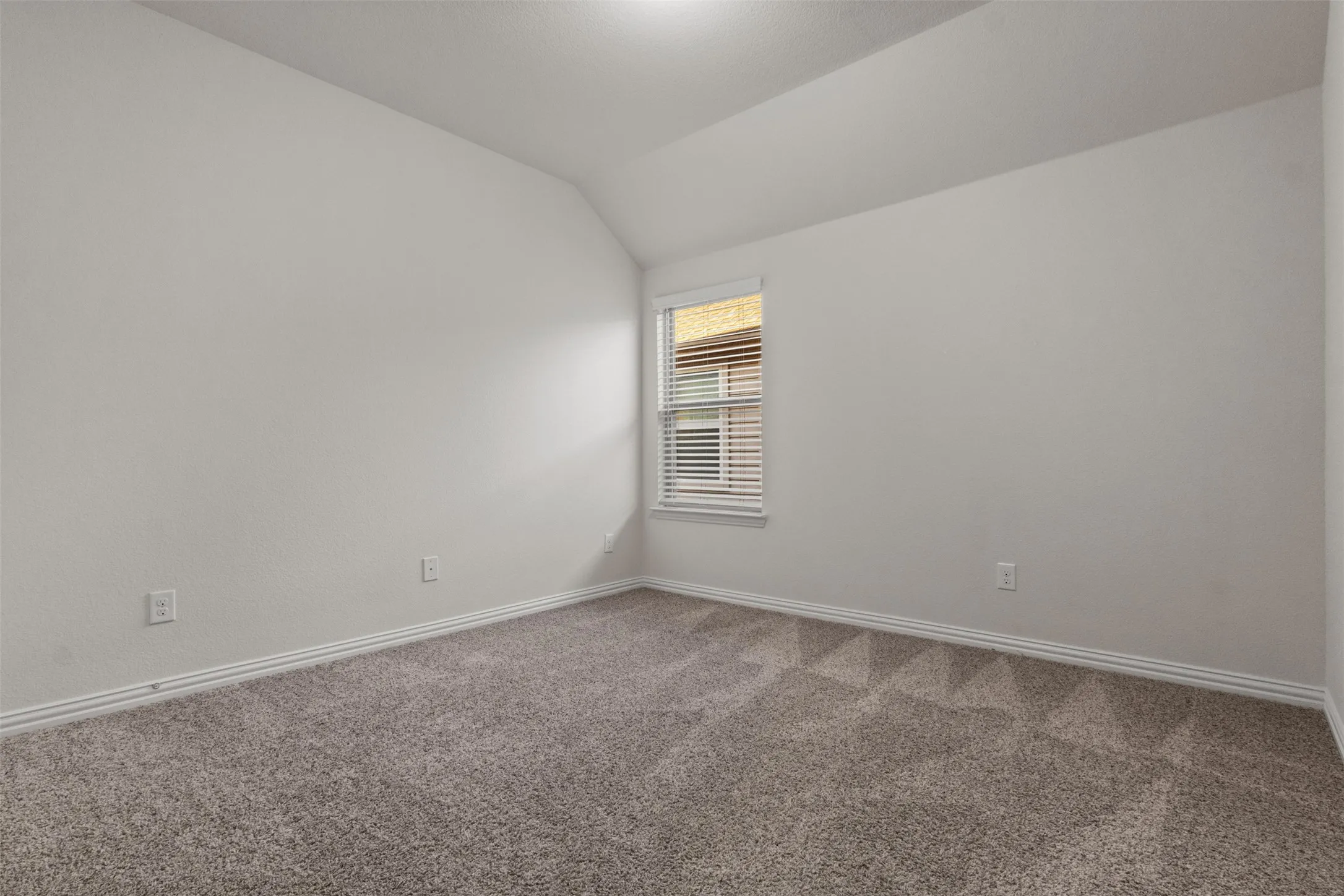 Carpeted room featuring a window with horizontal blinds and a sloped ceiling