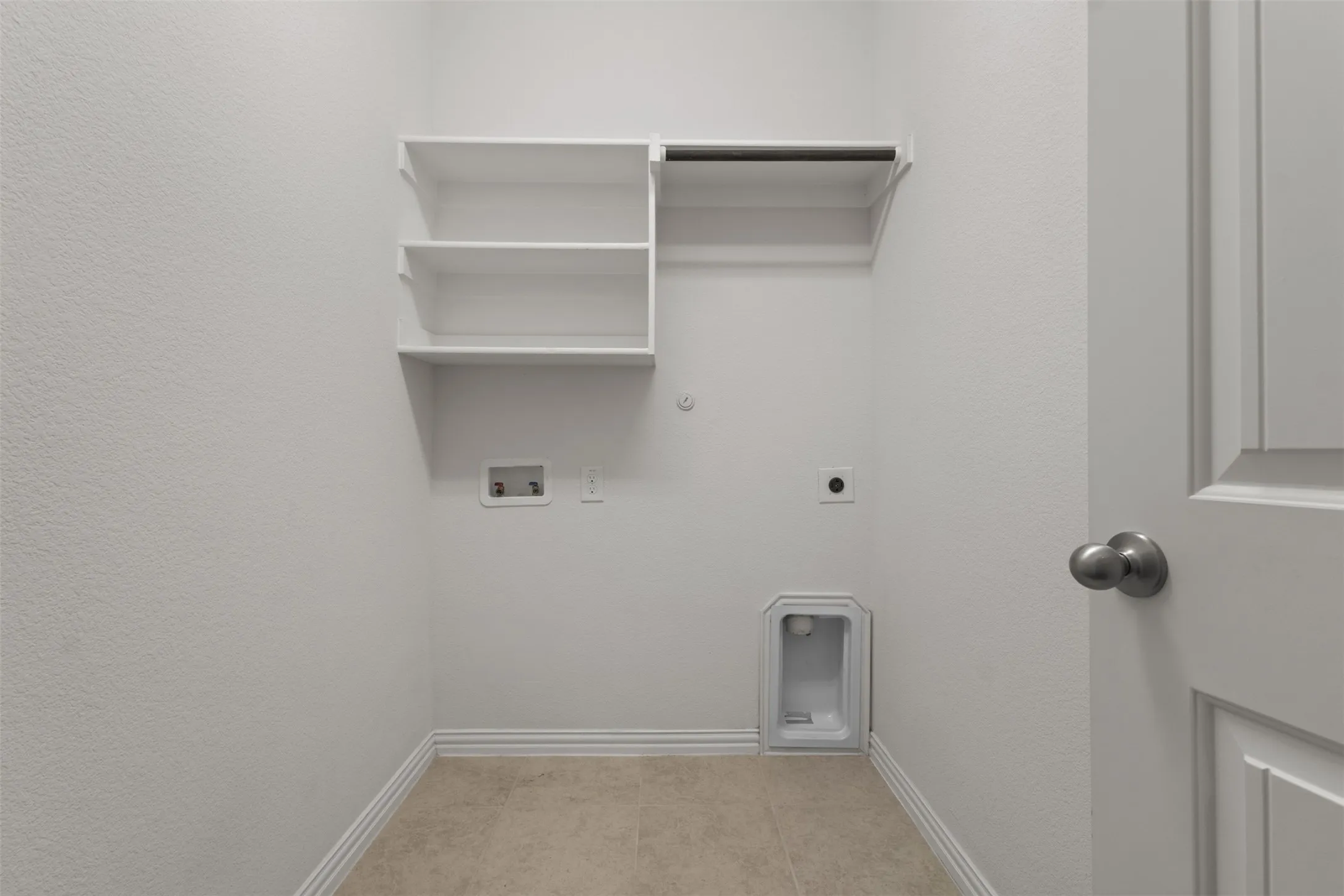 Laundry area featuring tiled flooring, built-in shelving, and a hanging rod