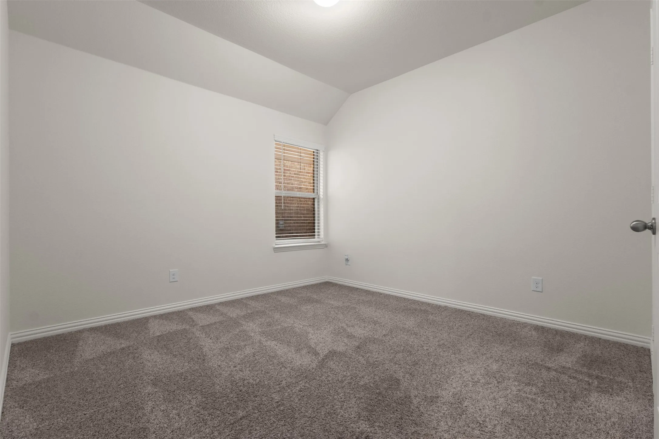 Neutral wall paint, textured carpet, window with blinds, white trim, and a ceiling light fixture