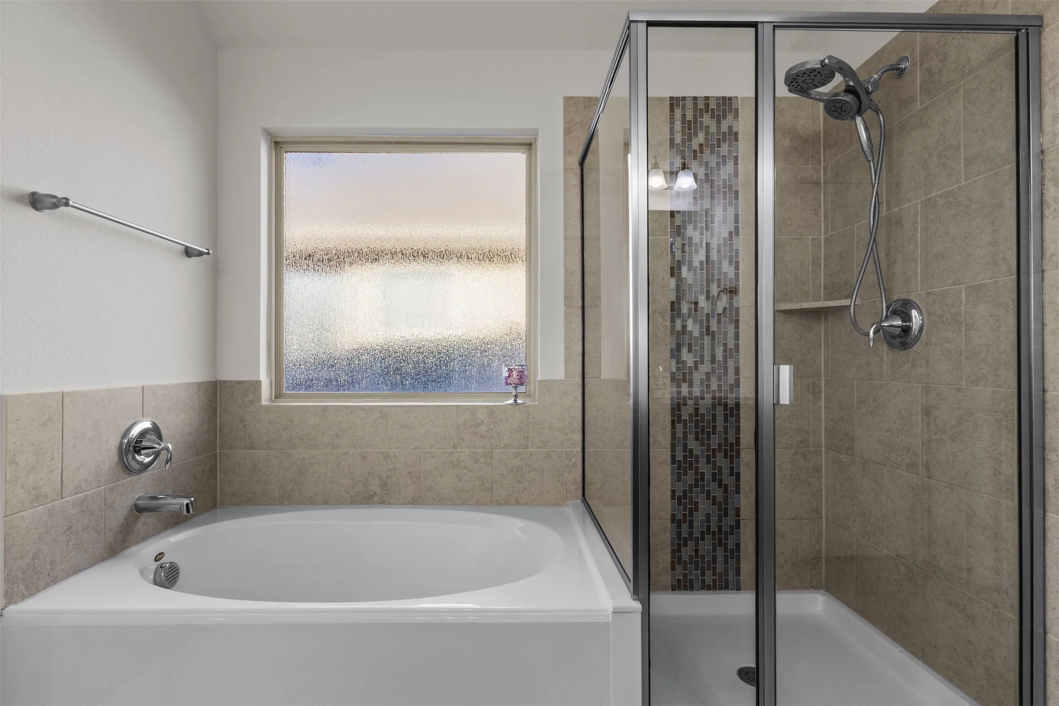 Soaking tub with chrome fixtures, tiled shower with glass enclosure, built-in shower niche, and mosaic tile accent